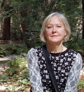 image of a woman with black and white print dress standing, a green forest in the background