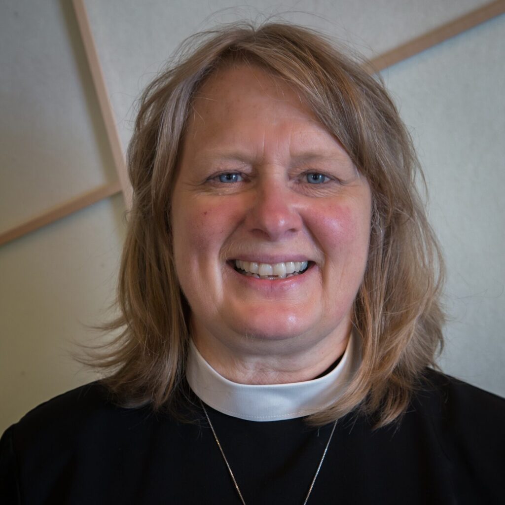 image of a woman smiling, wearing a black top with clergy collar