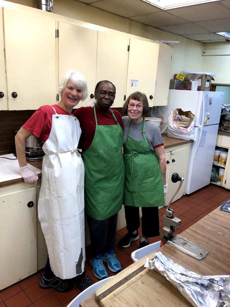 image of three women standing in a kitchen wearing aprons